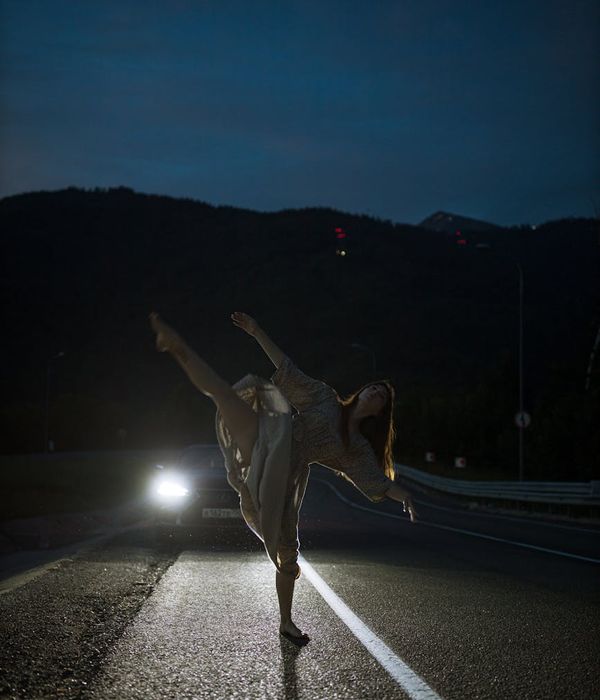 A woman performing a fluid motion exercise in a calm, dark environment with teal light accents.